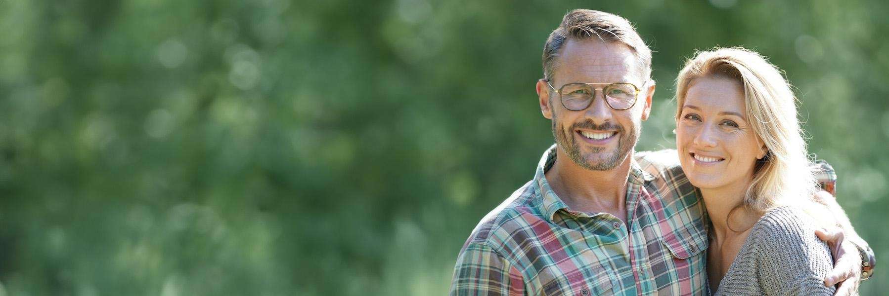 Smiling middle-aged couple outdoors showing confidence from healthy teeth and dental implants in Ham