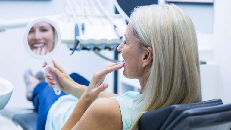 woman admiring her smile after teeth whitening in hampton park
