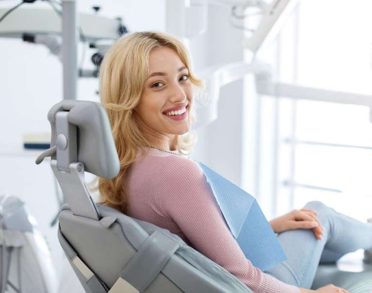Smiling woman sitting in a dental chair during consultation for dental implants and bone grafting so