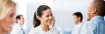Smiling woman talking with colleagues, highlighting stress as a factor in teeth grinding and TMJ iss